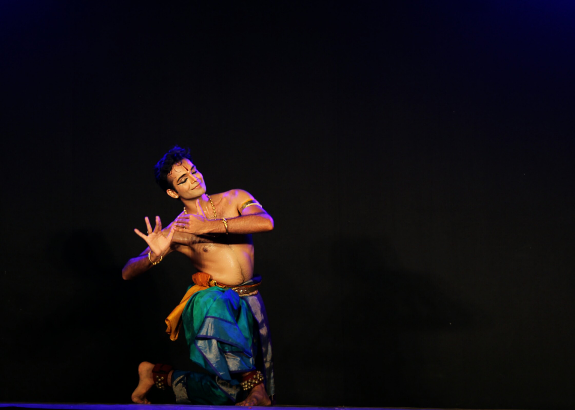Man dancing with bare chest and teal pants